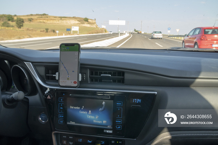 Mobile phone runs a navigation app and stick on dashboard of a hybrid car. Effective using of navigation devices create economy for automobiles.