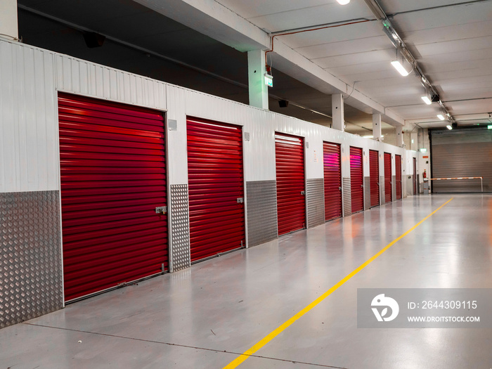 Long row of red color doors of self storage facility. Service to keep safe extra belongings. Nobody. Selective focus. Clean and well run business.