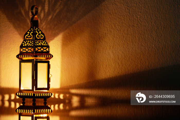 Ornamental Arabic lantern with burning candle glowing at night.