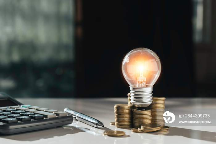 Coins and light bulb on table for saving money,energy concept.