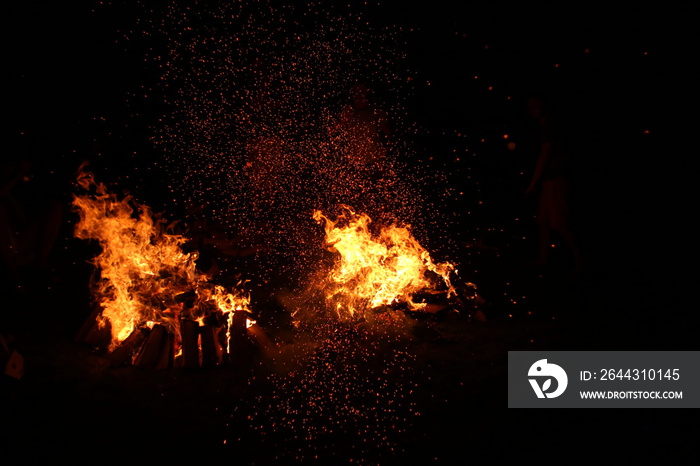 the flame of a burning bonfire on a black background and sparks