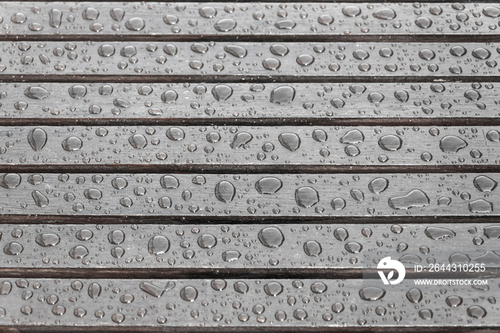 Wooden planks covered by water drops, background for rainy weather. Wet brown boards close up. Selective focus