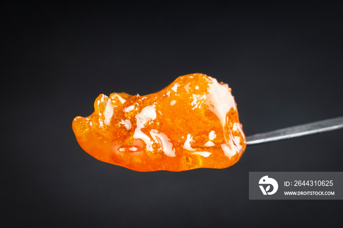 cannabis golden dab in dark, thc resin wax close up