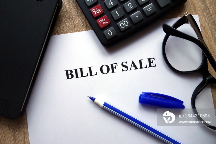 Bill Of Sale document, pen, glasses and calculator on   desk