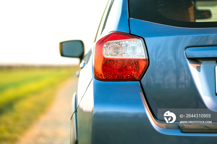 Closeup of rear red taillight and mirror of new clean blue SUV off-road car on rural road