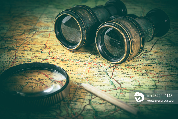 Magnifying glass and binoculars on the old map.