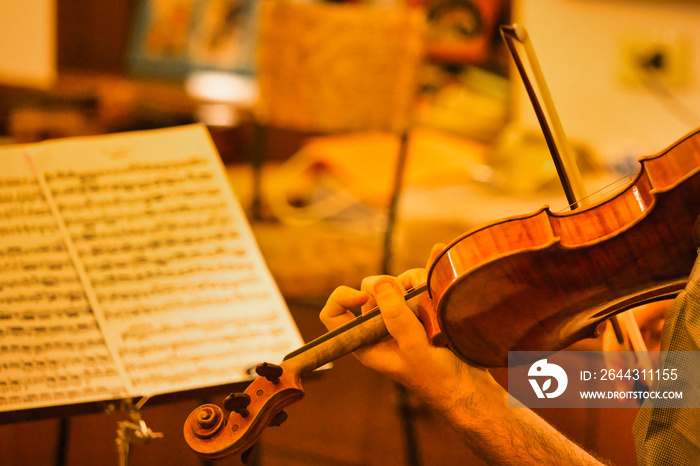 Closeup of the musician’s hand is playing a violin in an orchestra