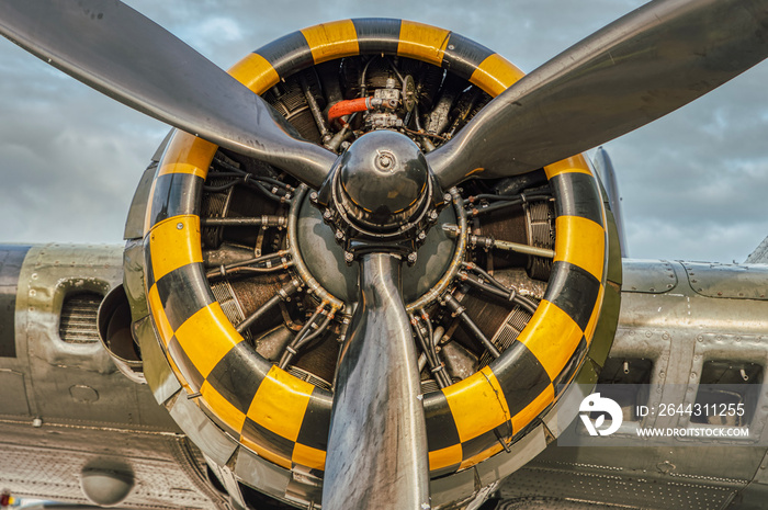 9 cylinder combustion engine with yellow, black square pattern. Nine chamber, air cooled radial motor with propeller closeup on heavy military bomber airplanes or aircraft used in the second world war