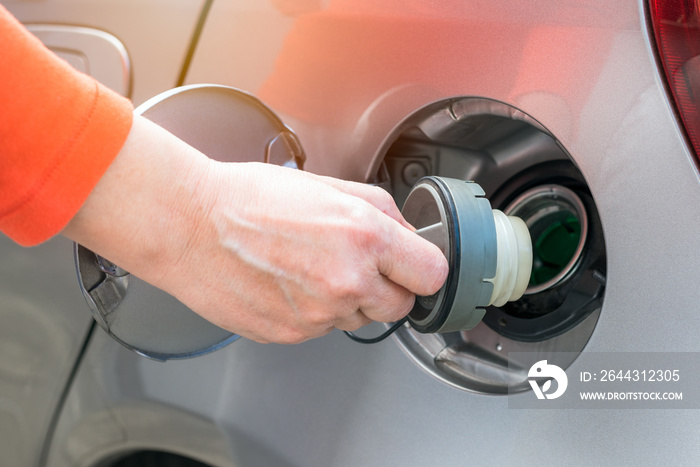 Woman removing the filler cap of a diesel car at a petrol station. Selective focus