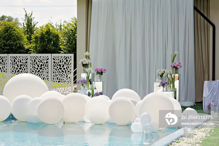 Decorations for the wedding ceremony by the pool with blue water.