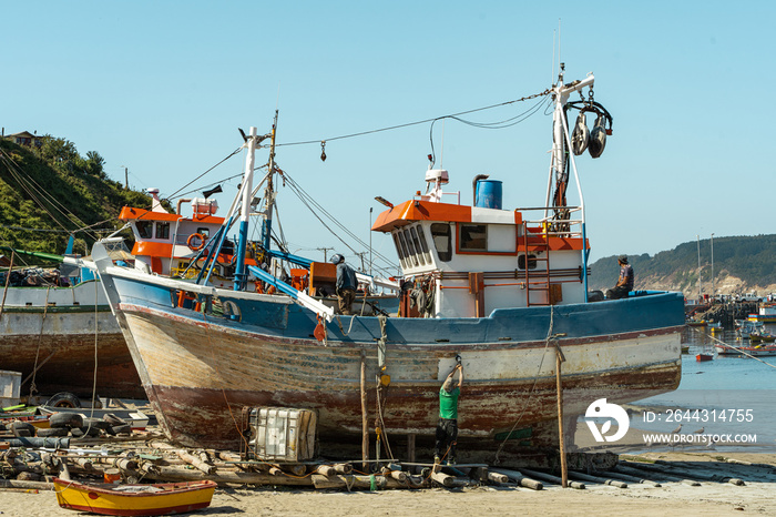 Vertical shot of boats under repair in Caleta Tumbes with beach and small boats below, Chile