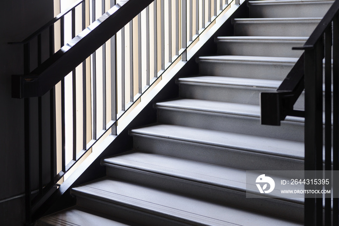 Empty Modern Concrete Staircase and black steel handrail with natural light, staircase in modern building - Dark Tone