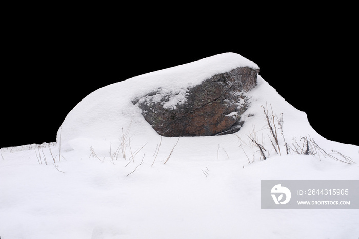 natural stone in snow isolated on black background