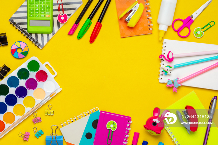 Back to school, education concept. Yellow backpack with school supplies - notebook, pens, ruler, calculator, scissors isolated on yellow background