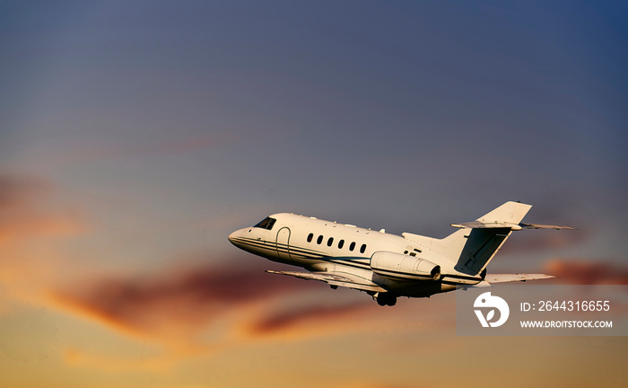 Private airplane jetliner flying above clouds in beautiful sunset light. Travel and business concept. Backside view