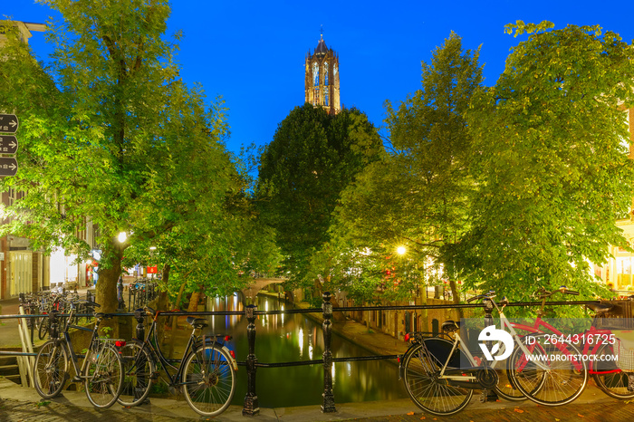 Dom Tower and bridge with bikes over canal Oudegracht in the night colorful illuminations in the blue hour, Utrecht, Netherlands