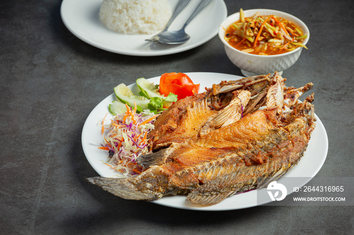 Fried snapper in a plate placed on a black background