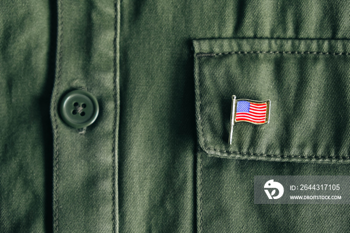 USA flag pin badge on green jacket pocket. Top view. Copy, empty space for text