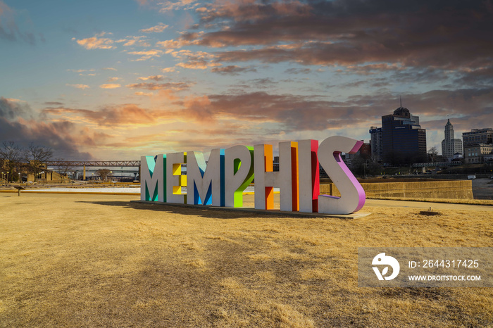 a gorgeous shot of the colorful Memphis sign with gorgeous red sky and powerful clouds at sunset with yellow winter grass at Mud Island Park in Memphis Tennessee USA