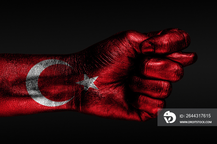 A hand with a painted Turkey flag shows a fig, a sign of aggression, disagreement, a dispute on a dark background.