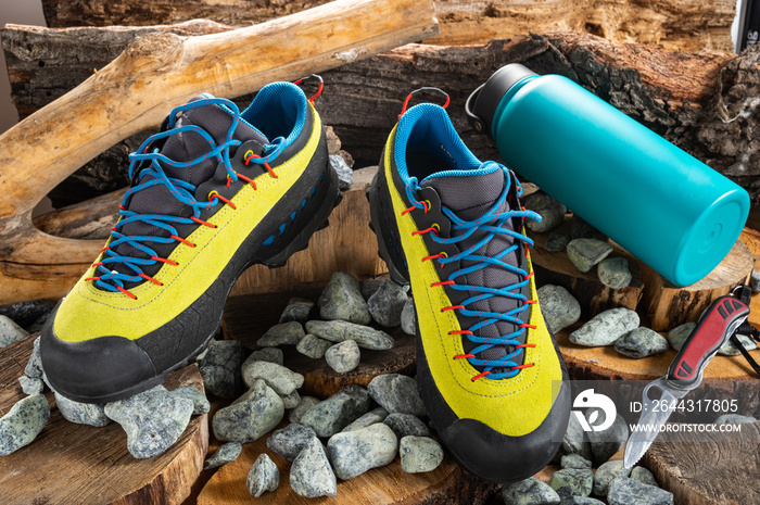 Hiking shoes and tourist flag and knife. Shoes on stones and branches