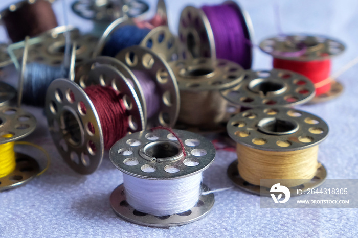 Multicolored threads on the bobbin from the sewing machine on a blurred background from the other bobbins