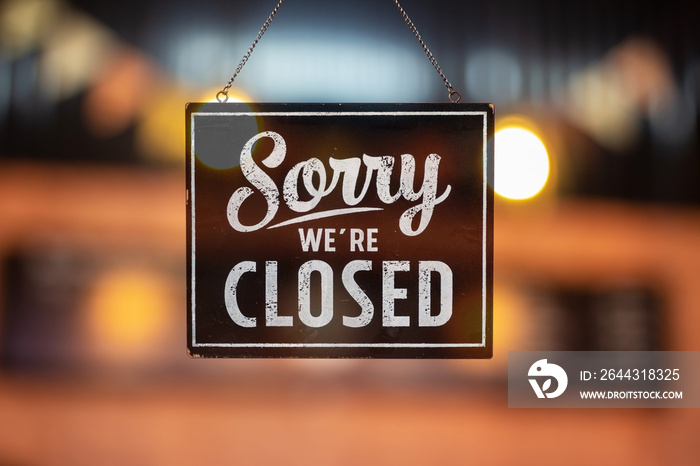 Sorry we’re closed sign. grunge image hanging on a glass door.