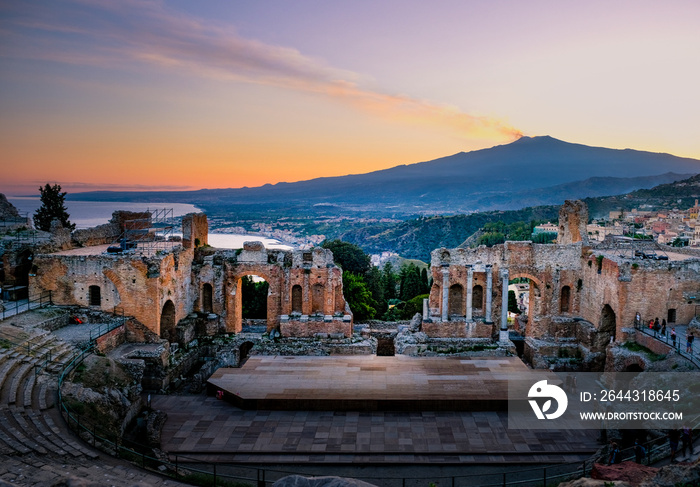 Ruins of Ancient Greek theatre in Taormina on background of Etna Volcano, Italy. Taormina located in Metropolitan City of Messina, on east coast of island of Sicily Europe