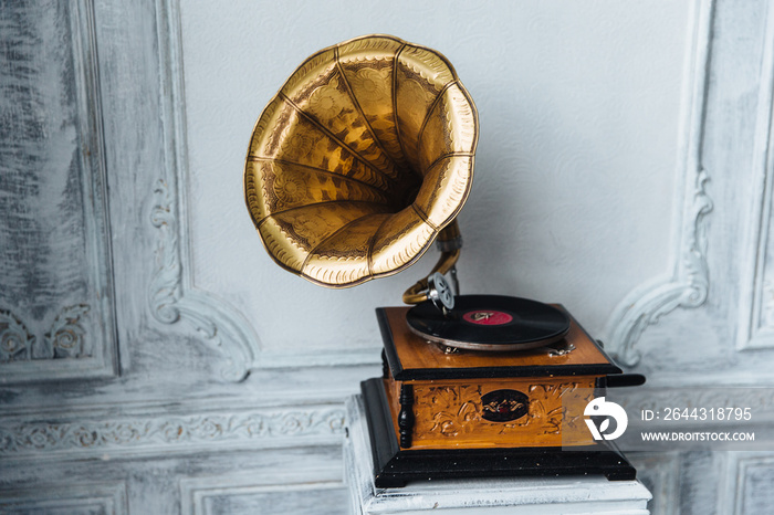 Old gramophone with horn speaker stands against anicent background, produces songs recorded on plate. Music and nostalgia concept. Gramophone with phonograph record