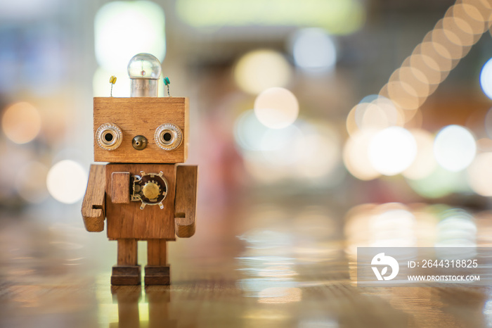 Retro wood robot with light bulb on the head standing on the table with bokeh light background, nature and energy concepts.