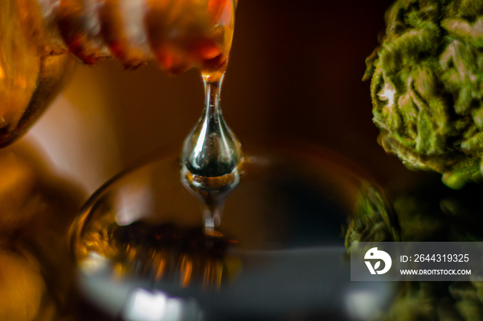 Medical Oil Drop of Cannabis - brown apothecary jar with oil drop and marijuana flower on the brown background.