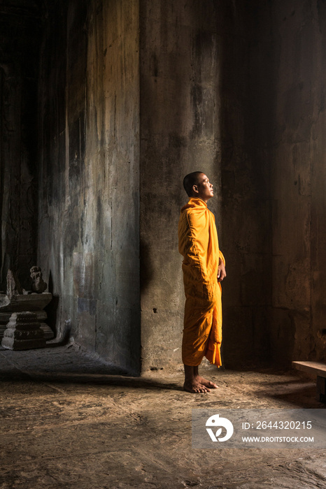 Young Buddhist monk standing inside temple in Angkor Wat, Siem Reap, Cambodia