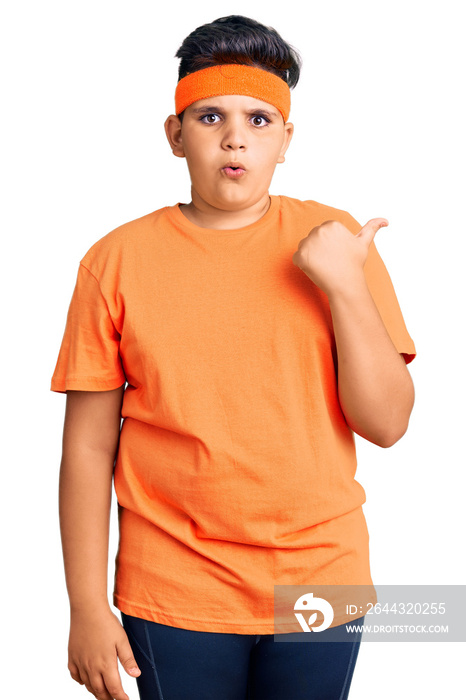 Little boy kid wearing sportswear surprised pointing with hand finger to the side, open mouth amazed expression.