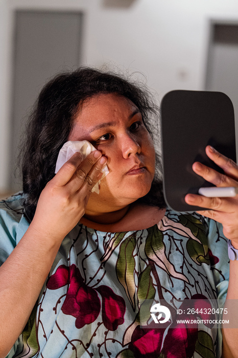 Plus size female removing her make up with a make up wipe