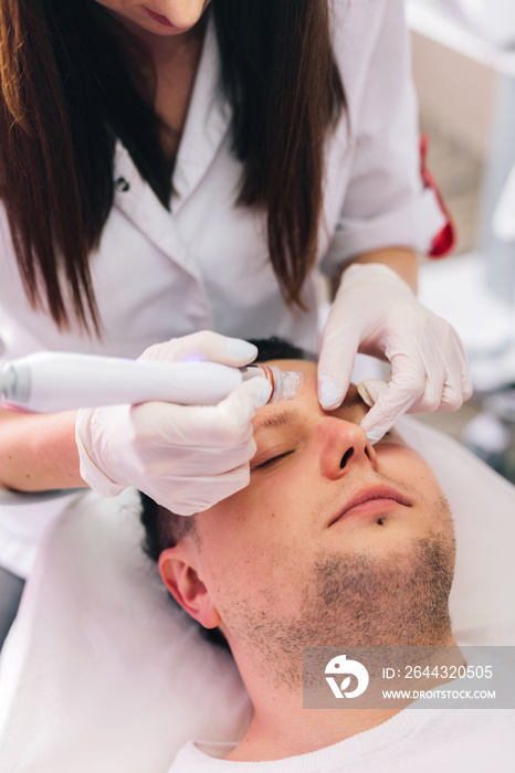 Cosmetologist doing hydrafacial treatment on man face