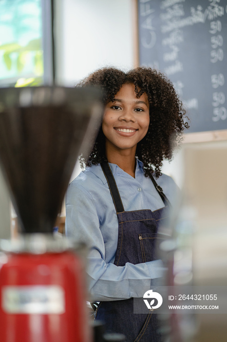 Smiling african american barista standing behind the coffee shop counter accepting customers, food and drink concept