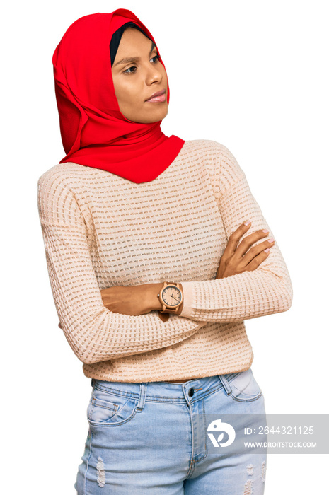 Young african american woman wearing traditional islamic hijab scarf looking to the side with arms crossed convinced and confident