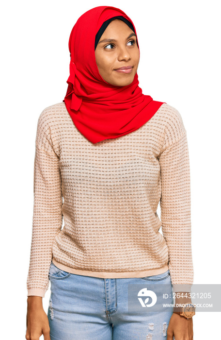 Young african american woman wearing traditional islamic hijab scarf smiling looking to the side and staring away thinking.