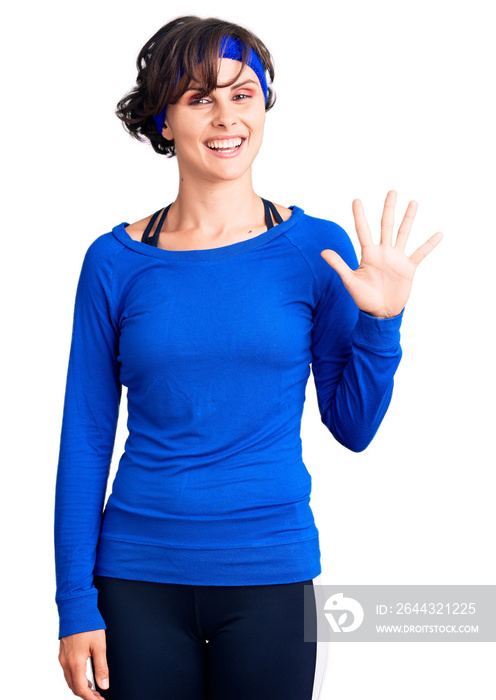 Beautiful young woman with short hair wearing training workout clothes showing and pointing up with fingers number five while smiling confident and happy.