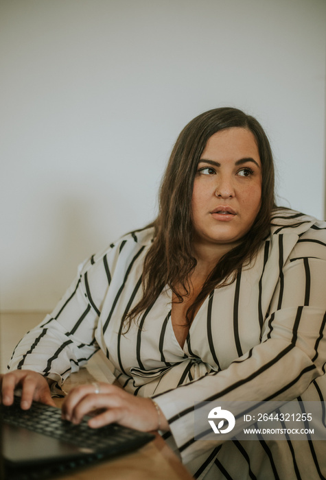 plus size metis woman works on computer with serious expression