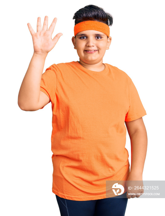 Little boy kid wearing sportswear showing and pointing up with fingers number five while smiling confident and happy.