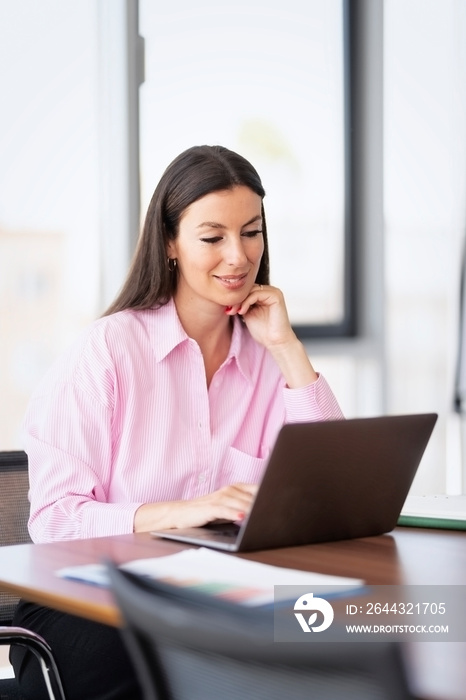 Confident businesswoman using a laptop while sitting at the office