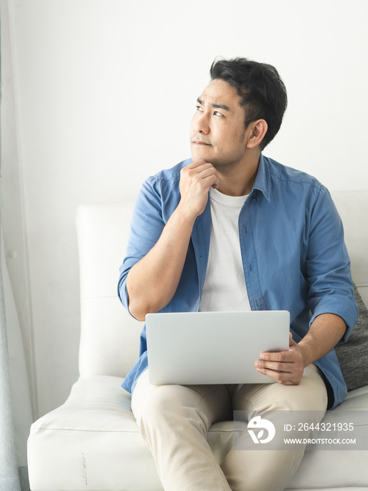 Stressed Asian man using laptop at home, lifestyle concept with copy space.