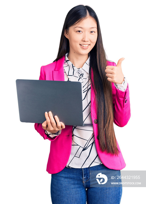 Young beautiful chinese woman using laptop smiling happy and positive, thumb up doing excellent and approval sign