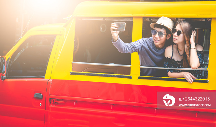 A couple of blogger tourists from Southeast Asia. Visit Phuket in Thailand are selfies on tuktuk. Captured in the old town of Phuket during write travel reviews with sunlight in travel concept .