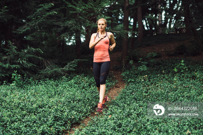 Caucasian woman running on forest trail wearing sport clothes