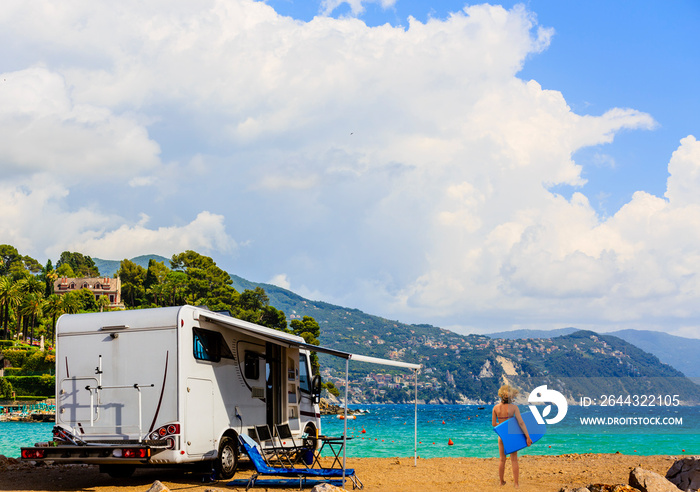 Camping RV travel with camper, summer beach. Happy smiling beauty girl on mototorhome vacation.