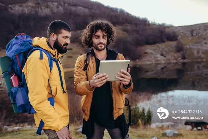 Lost hiker looking at the way through map on digital tablet during hiking in wilderness