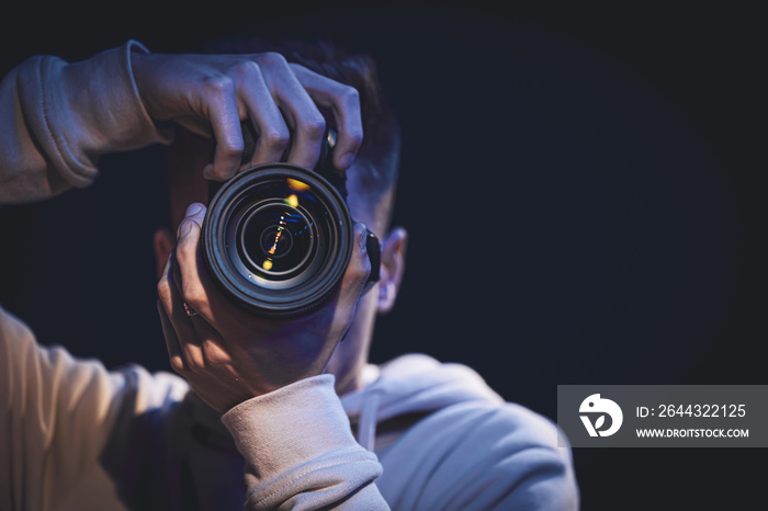 A man photographer with a camera takes a photo in the dark, copy space.