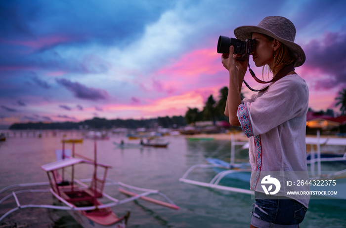 Photography and travel. Young woman in hat holding camera  with beautiful tropical sea view.